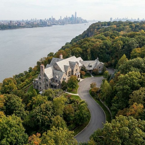 Aerial view of a stone Alpine NJ estate on the Palisades cliffs with the Hudson River and Manhattan skyline in the background