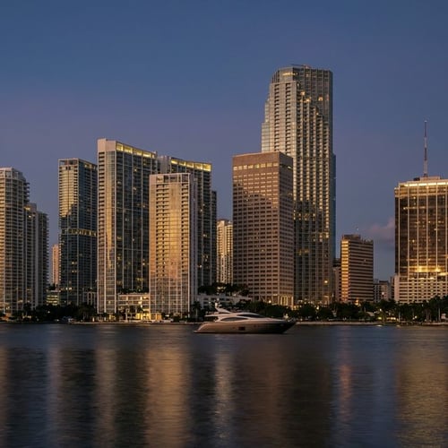 Modern high-rise condo towers illuminated against a dusky sky in Miami's financial district